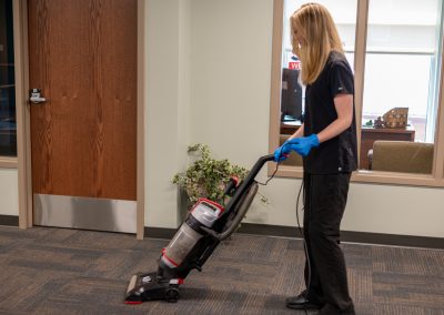 a cleaning professional vacuuming a rug