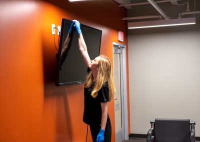 a cleaning professional whiping & dusting a television