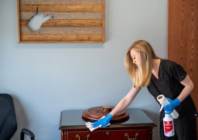 a female cleaning professional disinfecting an office space.