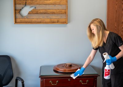 a female cleaning professional disinfecting a wooden counter top.